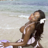 Black MILF Nikki Jaye unveils her increased breasts from her bathing suit top while on a beach