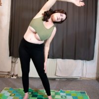 Stunning redhead solo chick Cleo lets out her enormous breasts during a yoga routine